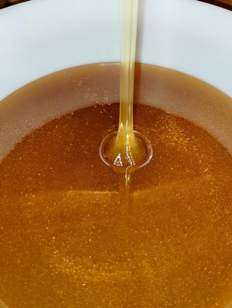 Flüssiger Honig fließt in einen Eimer.